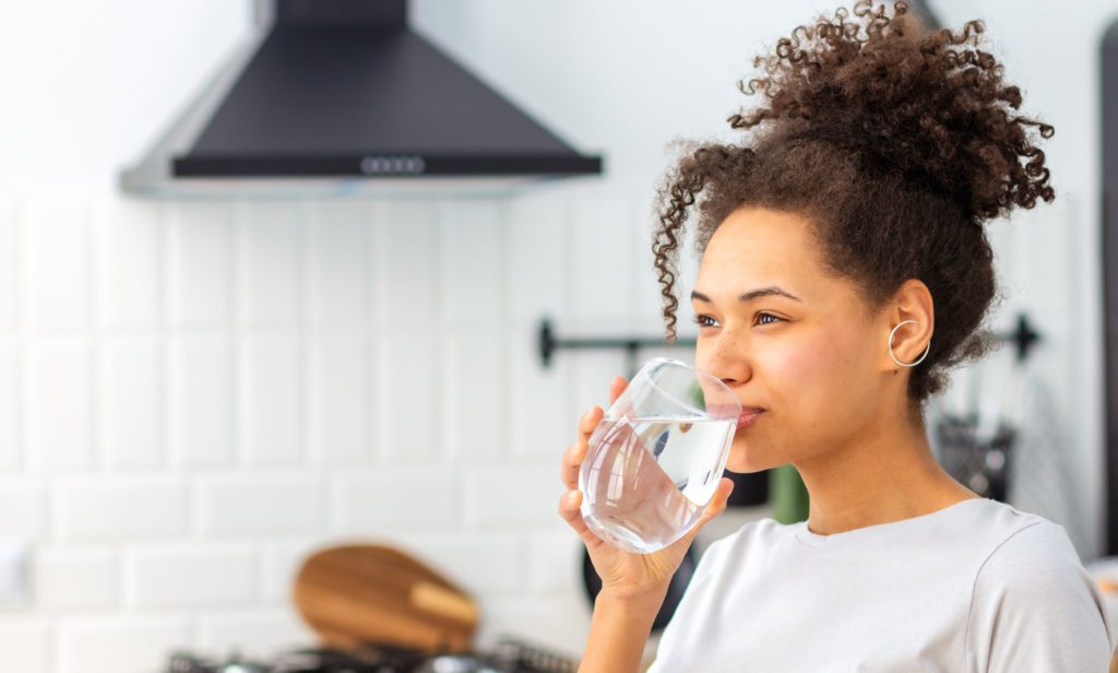 woman in kitchen sipping water from glass